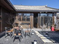 a room that has a small courtyard area with two tables and chairs in it near a fence