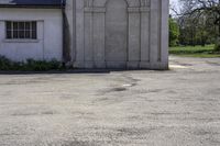 a white concrete building with an arched doorway and a door with columns in the front