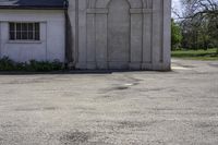 a white concrete building with an arched doorway and a door with columns in the front