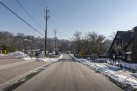 street view with cars parked on the left side of the road and power lines overhead