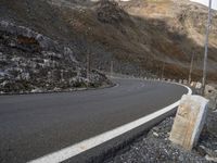 a stone sitting next to the side of a road in a mountainous area near a steep mountain