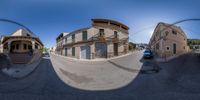 a fisheye view looking down a road towards houses on the ground and buildings along the street