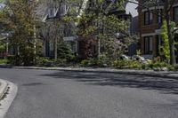 an empty street that is lined with small buildings in the distance are two rows of houses and trees