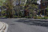 an empty street that is lined with small buildings in the distance are two rows of houses and trees