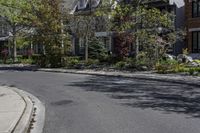 an empty street that is lined with small buildings in the distance are two rows of houses and trees