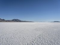 there is a snow field in the middle of nowhere on a clear day with some mountains in the distance