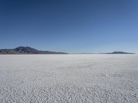 there is a snow field in the middle of nowhere on a clear day with some mountains in the distance