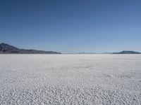 there is a snow field in the middle of nowhere on a clear day with some mountains in the distance