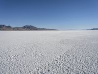 there is a snow field in the middle of nowhere on a clear day with some mountains in the distance