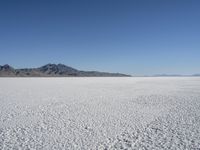 there is a snow field in the middle of nowhere on a clear day with some mountains in the distance