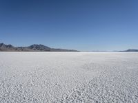 there is a snow field in the middle of nowhere on a clear day with some mountains in the distance