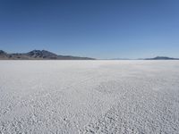 there is a snow field in the middle of nowhere on a clear day with some mountains in the distance