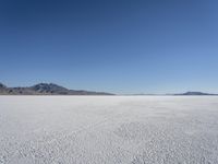 there is a snow field in the middle of nowhere on a clear day with some mountains in the distance