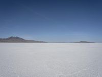 there is a snow field in the middle of nowhere on a clear day with some mountains in the distance