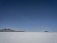 there is a snow field in the middle of nowhere on a clear day with some mountains in the distance