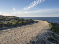 a sandy and rocky cliff on a clear day looking out at the sea and sky