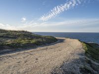 a sandy and rocky cliff on a clear day looking out at the sea and sky