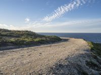 a sandy and rocky cliff on a clear day looking out at the sea and sky