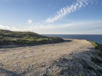 a sandy and rocky cliff on a clear day looking out at the sea and sky