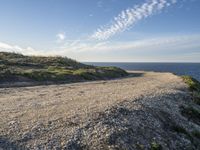 a sandy and rocky cliff on a clear day looking out at the sea and sky