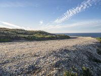 a sandy and rocky cliff on a clear day looking out at the sea and sky