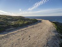 a sandy and rocky cliff on a clear day looking out at the sea and sky