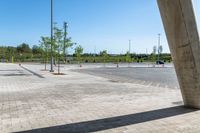 a sidewalk in the middle of a parking lot next to some tall poles and benches