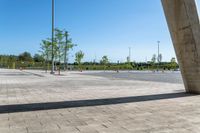 a sidewalk in the middle of a parking lot next to some tall poles and benches