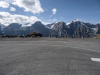 a parking lot with parked cars next to mountains with snow capped peaks in the background