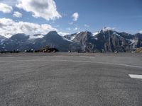 a parking lot with parked cars next to mountains with snow capped peaks in the background