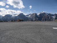 a parking lot with parked cars next to mountains with snow capped peaks in the background