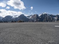 a parking lot with parked cars next to mountains with snow capped peaks in the background