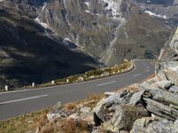 an empty mountain road running by a snowy mountain pass with a long mountain line in the distance