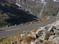 an empty mountain road running by a snowy mountain pass with a long mountain line in the distance