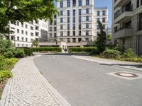 a paved street and trees in a large city area with a statue in the center of it