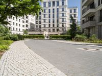 a paved street and trees in a large city area with a statue in the center of it