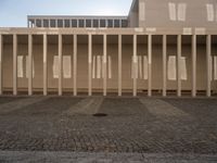 a room with columns near a building with light pouring through it and shadows in the windows