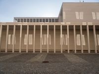 a room with columns near a building with light pouring through it and shadows in the windows