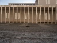 a room with columns near a building with light pouring through it and shadows in the windows