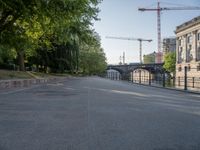 a tree lined road next to a body of water with lots of trees and a building under construction