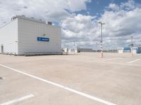 parking lot with building and parking spots against the cloudy sky with clouds in front of it