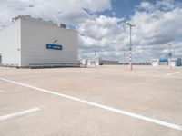 parking lot with building and parking spots against the cloudy sky with clouds in front of it