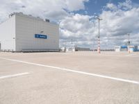 parking lot with building and parking spots against the cloudy sky with clouds in front of it