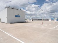 parking lot with building and parking spots against the cloudy sky with clouds in front of it