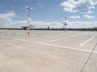 a large empty parking lot on a sunny day with bright clouds in the sky and lots of parking spaces