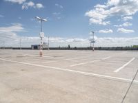 a large empty parking lot on a sunny day with bright clouds in the sky and lots of parking spaces