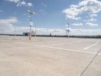 a large empty parking lot on a sunny day with bright clouds in the sky and lots of parking spaces