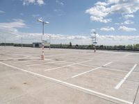 a large empty parking lot on a sunny day with bright clouds in the sky and lots of parking spaces