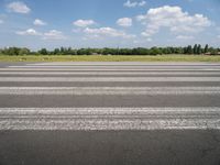 a man riding his motorcycle down an empty road near green grass and shrubs in the background