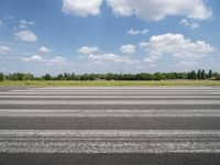 a man riding his motorcycle down an empty road near green grass and shrubs in the background